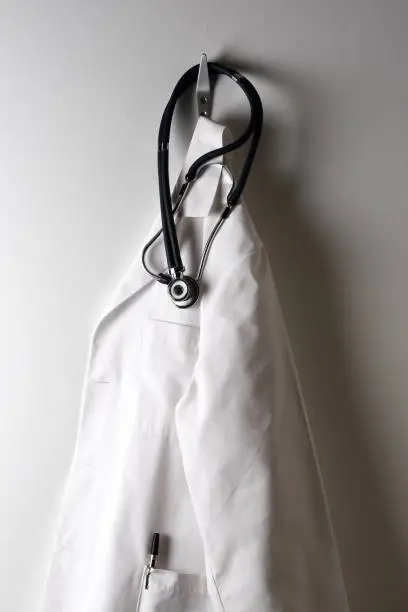 A Doctors White Lab Coat Hanging on a Hook with Stethoscope.