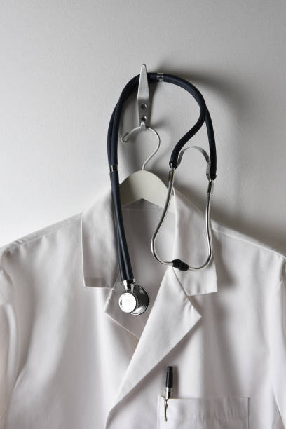 istock A Doctors White Lab Coat on a  hanger on a Hook with Stethoscope, pen in pocket. 1283603837
