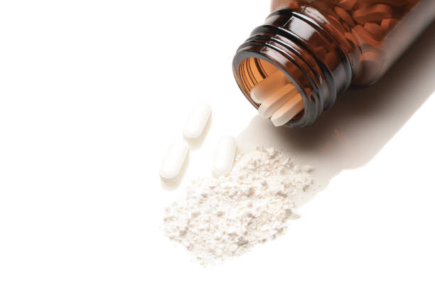 Closeup of an apothecary bottle on its side with a white powder from crushed pills spilling out Opioid Crisis Concept: Closeup of an apothecary bottle on its side with a white powder from crushed pills spilling out. Whole pills fill the brown bottle. fentanyl stock pictures, royalty-free photos & images