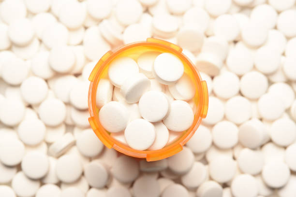 prescripción embotellada llena de píldoras rodeadas por más de los mismos comprimidos - fentanyl fotografías e imágenes de stock
