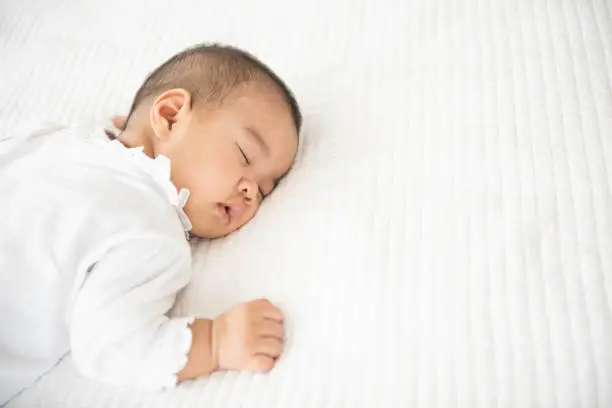 Newborn asian baby girl sleep on white bed relaxing feelgood happy. people health care concept.