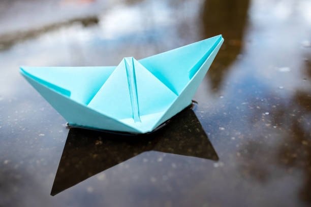 istock one blue paper ship floating on a water surface. outdoors. autumn season. greeting card with copy space. leadership conceptual. freedom concept 1283609656