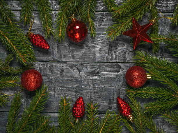 istock Spruce branches with red glass ornaments on a wooden background. Space for text. 1283616622