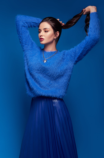 Moda de estudio: encantadora joven vestida con falda azul y suéter. Retrato de chica hermosa photo