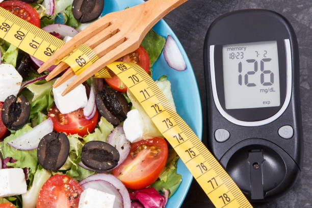 Glucose meter with sugar level, centimeter and greek salad. Diabetes, slimming, healthy lifestyles and nutrition stock photo