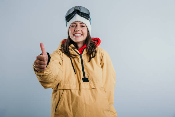 Thumbs up, mountains here we come A beautiful girl standing showing a big smile, satisfaction, and thumbs up, already fully prepared for the skiing, mountains, adventure, fresh air, and joy. Cap jacket and goggles on. thumbs up for skiing stock pictures, royalty-free photos & images