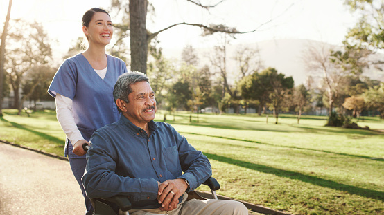 Shot of a senior man in a wheelchair spending time in the park with his nurse