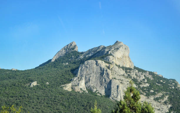 istock Rocky mountain tops covered with green trees against a bright Sunny sky 1283632797