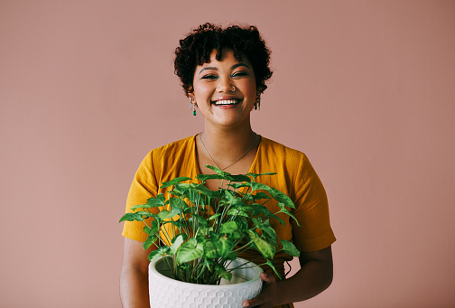Portrait of a young woman holding a plant against a brown background