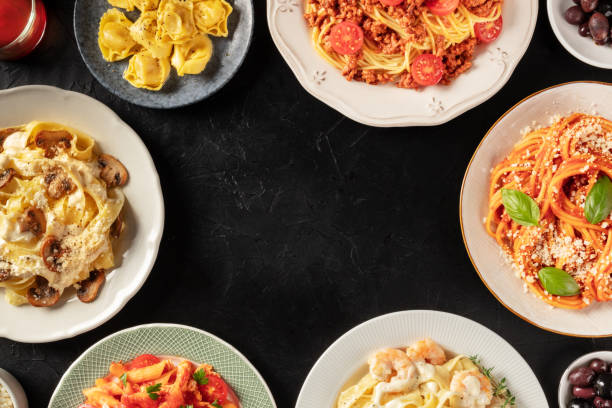 istock Italian pasta dishes forming a frame for copy space, overhead shot on a dark background. Pastas with meat, vegetables, seafood, chicken and mushrooms 1283634177