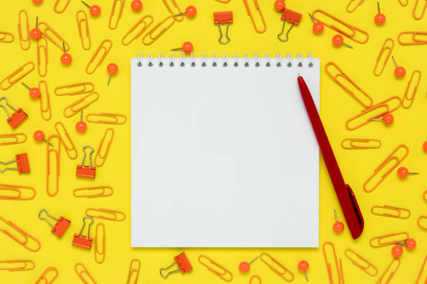 istock Notepad and red pen on a yellow paper background. Open notebook and supplies on the table. Template with copy space, flat design, layout. Planning concept, education. Workspace. 1283636797