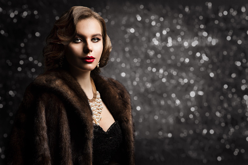 Retro woman portrait. Beautiful girl with red fur in the style of the 20s or 30s. Old fashionable Finger Wave makeup and hairstyle.