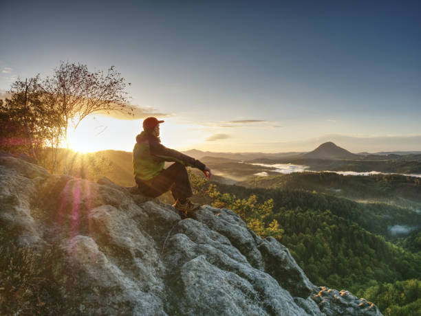istock Man Take Rest On Peak. Traveler With Green Windproof Jacket Resting On Ground And Admires Peaks 1283655280