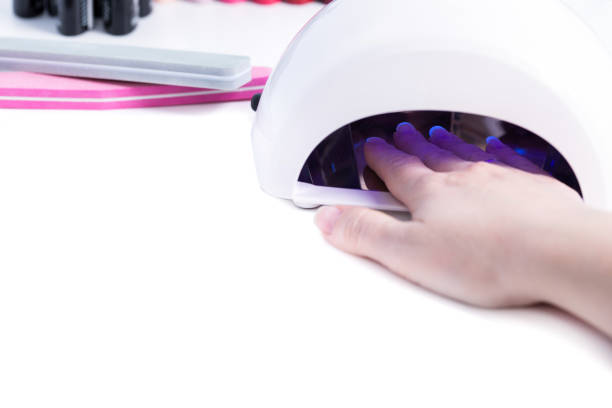 istock Woman put hand in led lamp dryer on white table 1283666970