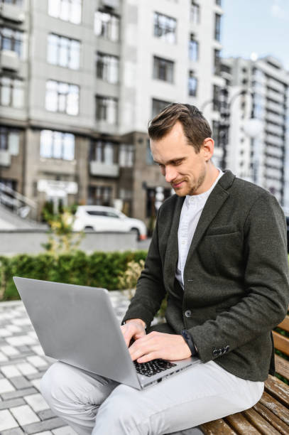 a young guy with laptop works outdoors - surfing wireless vertical outdoors lifestyles imagens e fotografias de stock