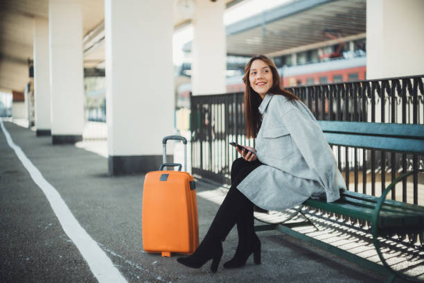 istock Young woman waiting on station and using smart phone 1283668402
