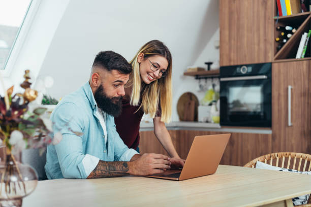 We love spending time together Shot of young couple spending their day indoors while using a lap top credit score photos stock pictures, royalty-free photos & images