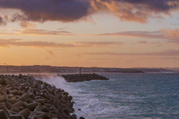 Peniche lighthouse with Supertubos beach on the background at sunset with waves crashing, in Portugal Peniche lighthouse with Supertubos beach on the background at sunset with waves crashing, in Portugal beautiful beach in carvoeiro algarve portugal stock pictures, royalty-free photos & images