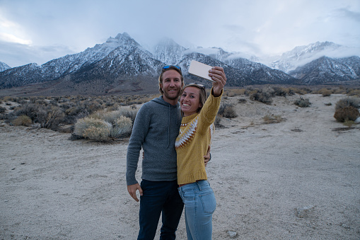 Cheerful young couple taking a selfie portrait with the beautiful landscape of the Sierra Nevada mountains in California, USA
People travel nature communication concept