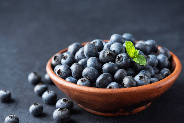 istock Blueberries in bowl over black background 1283669762