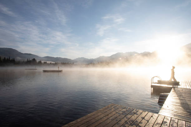 istock Man relaxes on lakeside dock at sunrise 1283671445