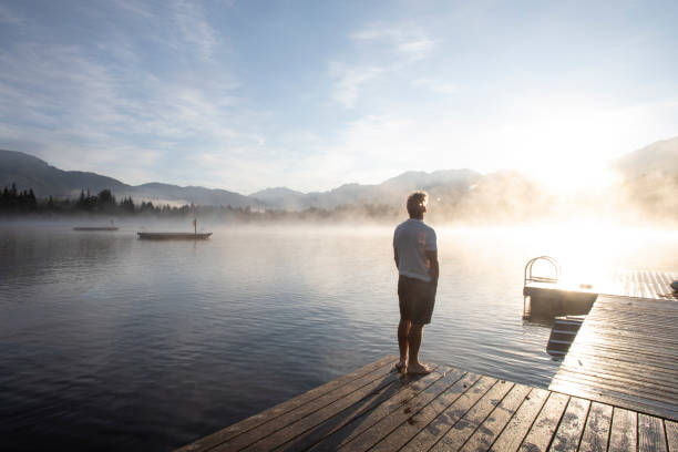 Man relaxes on lakeside dock at sunrise