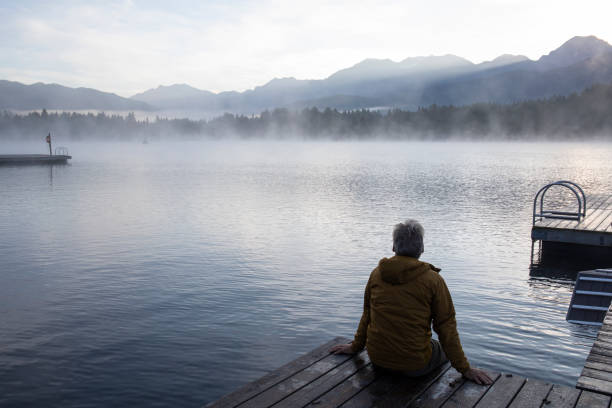 istock Man relaxes on lakeside dock at sunrise 1283672441