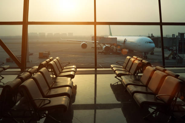 istock Aircraft flight preparation - fueling, catering, baggage services before airplane takeoff. Waiting area with chairs in international airport terminal with behind a window. 1283672934