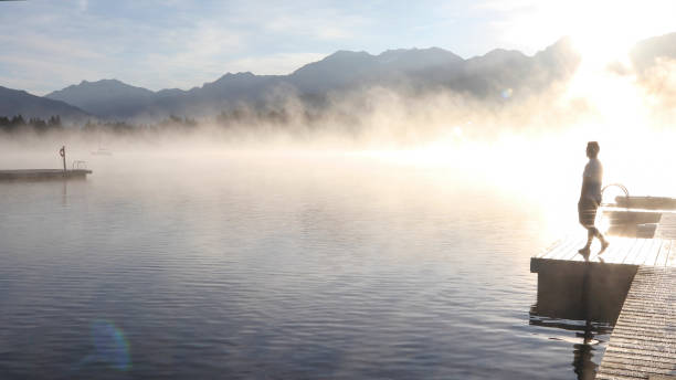 istock Man relaxes on lakeside dock at sunrise 1283673400