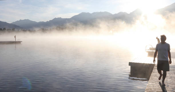 istock Man relaxes on lakeside dock at sunrise 1283673530