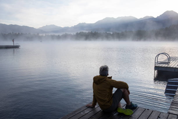 istock Man relaxes on lakeside dock at sunrise 1283674827