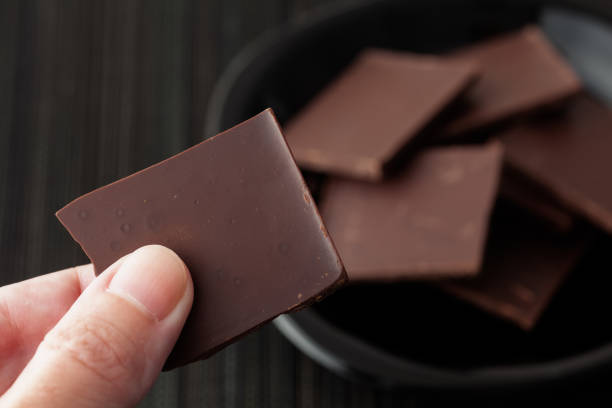 istock Man holding a piece of broken dark chocolate 1283674970