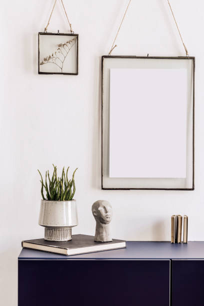 istock Stylish interior of living room with bluenavy commode, mock up poster frame, decoration, book and elegant personal accessories in modern home decor. Template. 1283676390