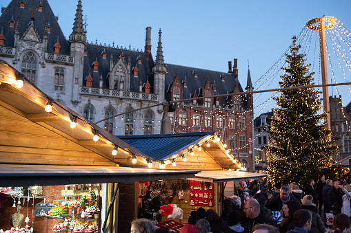 Bruges, Belgium - November 30, 2019 - Traditional Christmas market with stalls, decorated Christmas tree at the Bruges main square