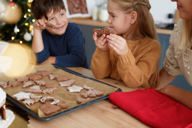 children tasting homemade cookies baked with mother - pastry cutter family holiday child imagens e fotografias de stock