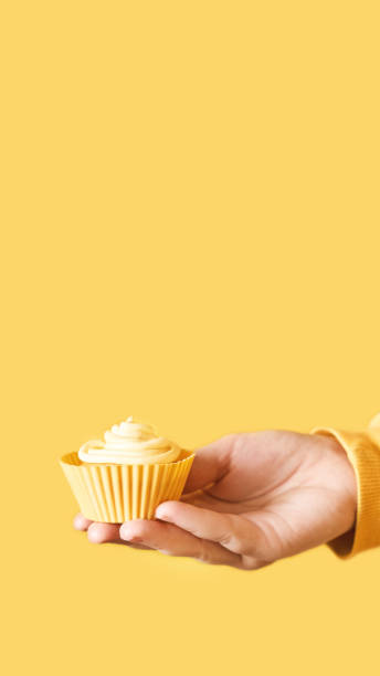 istock Yellow monochrome bakery. Sustainable cupcake cup. Hold in hand 1283677059