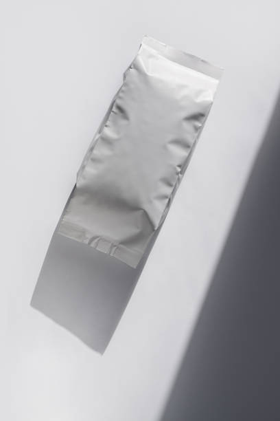 istock Blank foil food or drink bag on white background in minimal style, natural light shadow. Monochrome coffee pack flat lay 1283677984