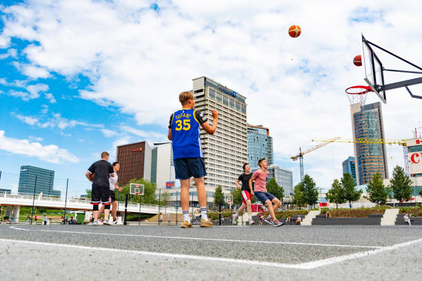 Street basketball in the city Vilnius, Lithuania - July 18 2020: Street basketball in the city. Boys performing with city and skyscrapers background asphalt basketball court stock pictures, royalty-free photos & images