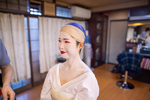 Japanese woman in special white face make-up smiling, before wearing Geiko / Maiko kimono