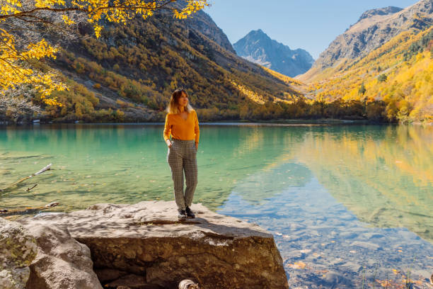 привлекательная женщина на хрустальном озере в осенних горах. горное озеро и девушка-турист - lake alaska mountain mountain range стоковые фото и изображения