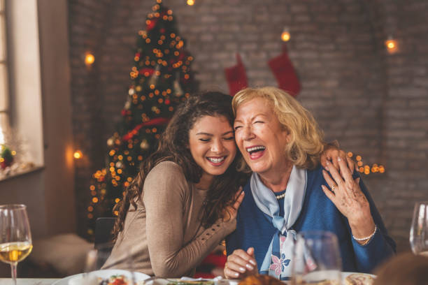 moeder en dochter die tijdens het diner van kerstmis koesteren - avondmaaltijd fotos stockfoto's en -beelden