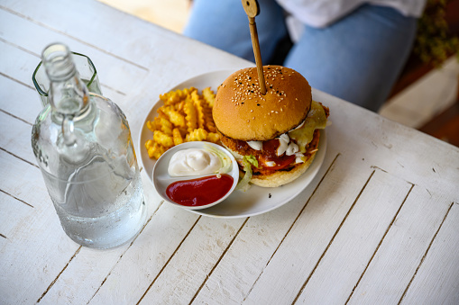 Elevated view of burger and fries with ketchup and mayo, water bottle next to it, Nikon Z7