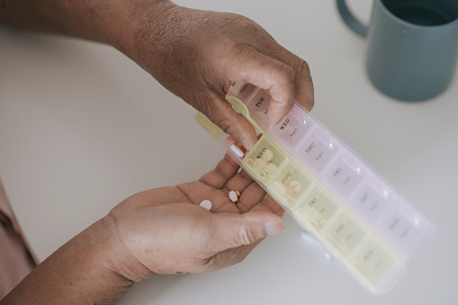 asian chinese Senior man putting medications in a daily pill organizer