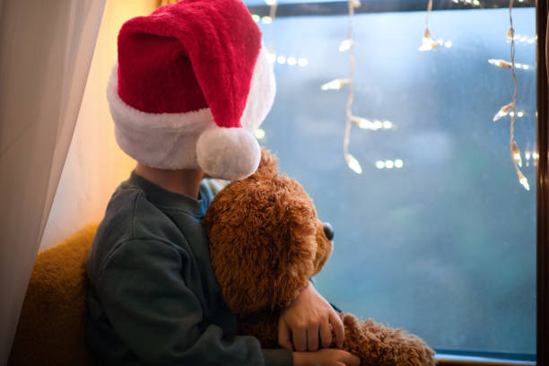 クリスマスに彼のテディベアとサンタの帽子で自宅の検疫でかわいい男の子 - sadness child little boys loneliness ストックフォトと画像