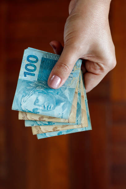 Hands holding Brazilian real notes Hands holding Brazilian real notes, money from Brazil, notes of Real, Brazil BRL banknote, Brazilian currency, economy and business. bottom the weaver stock pictures, royalty-free photos & images