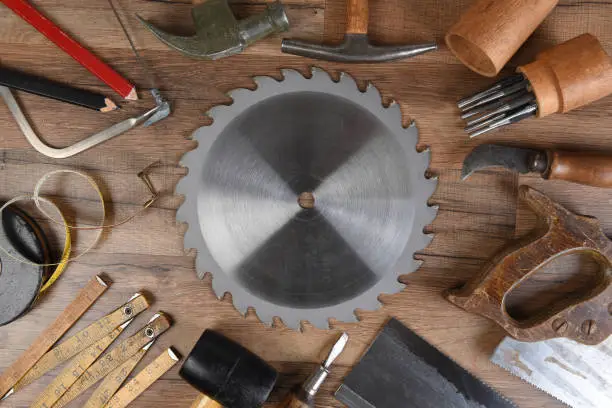 High angle closeup of a large group of tools arranged around a round table saw blade.