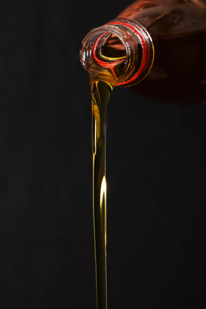 istock Pouring olive oil from a bottle on darck background 1283687396