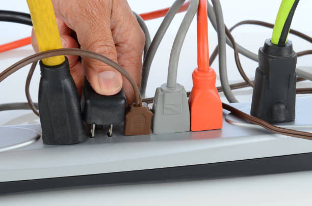 Man Inserting Plug into Power Strip Closeup of a mans hand inserting a plug into a crowded power strip. Frayed stock pictures, royalty-free photos & images