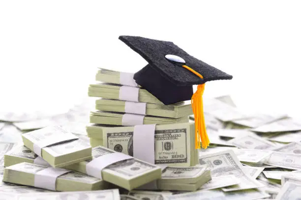 Photo of Mortarboard on a pile of money representing the high cost of higher education and bribery