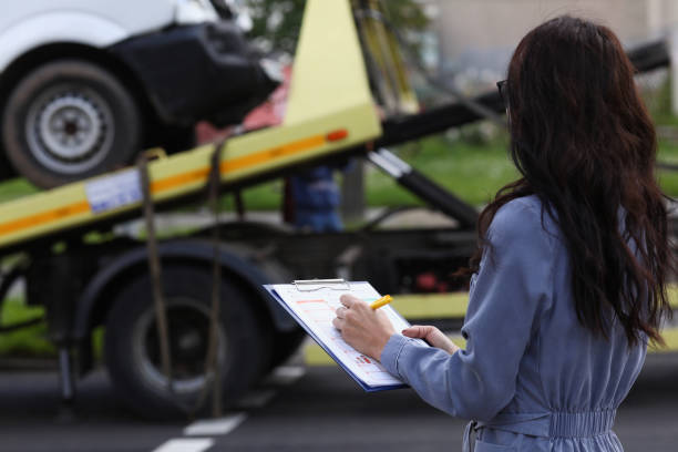 l’agent d’assurance de femme prépare des documents pour la voiture qui est enlevée par le camion de remorquage - tow truck photos photos et images de collection